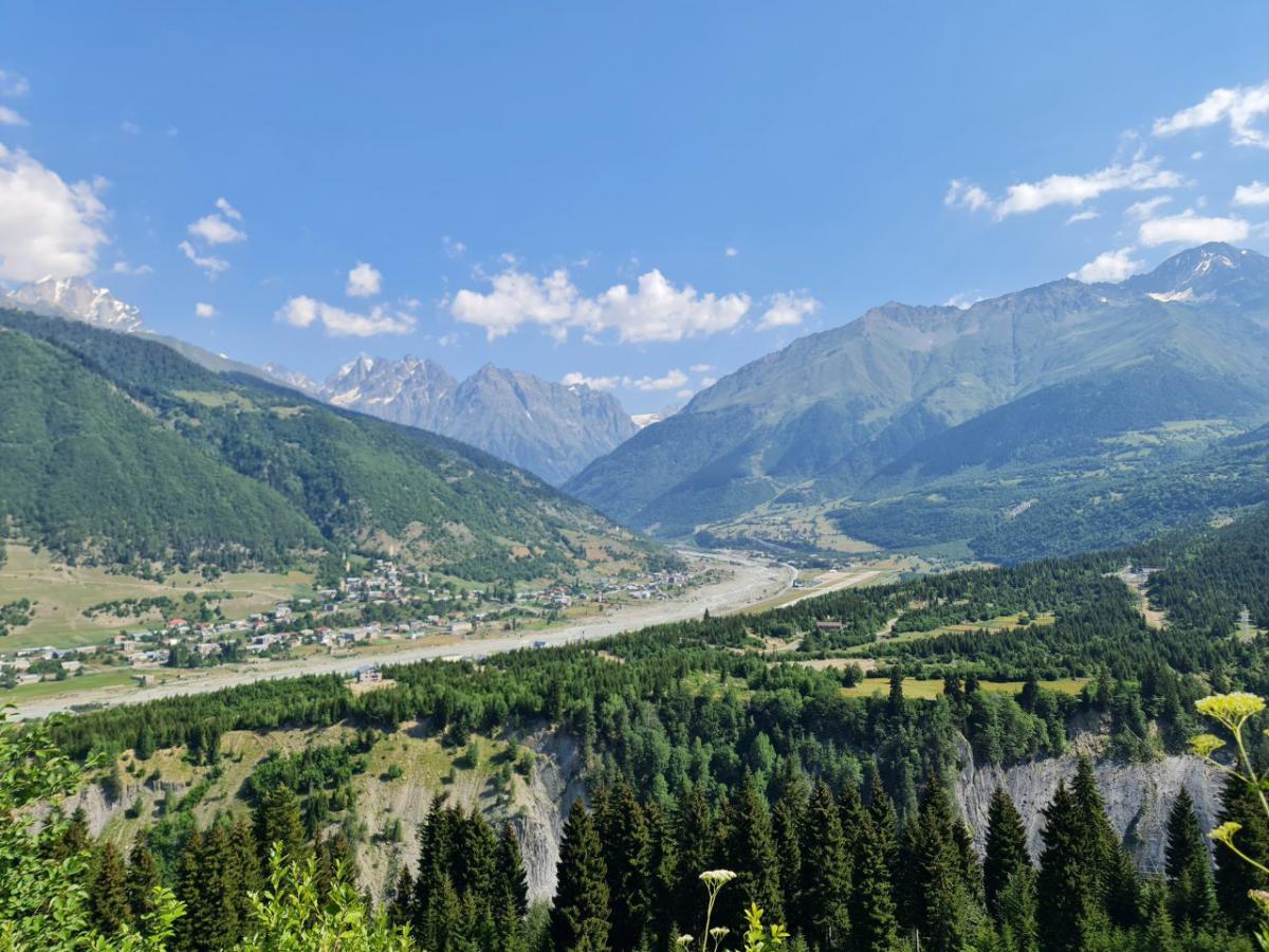  /></p><p>Cu fizicul intact și cu orgoliul un pic zgândărit pornesc spre destinație. Ushguli, oameni buni. Aproape ireal. Construite pe o culme, casele de piatră din sat poartă povara trecerii anilor și își trădează imediat scopul. Turnurile au fost construite pentru adăpostirea populației care a fost, timp de secole, în calea diverșilor invadatori. Peisajul natural este de așa natură, intervenția umană doar a completat cu aceste turnuri. Stânga-dreapta sunt doi munți golași, acoperiți de iarbă, iar în față, înainte… minunatul Șhara. Al treilea cel mai înalt vârf din Caucaz după Elbrus și Dîhtau, Șhara este cel mai înalt munte al Georgiei, 5210 metri. Acoperit de la mijloc în sus cu zăpadă, muntele este cu atât mai impresionant cu cât l-am prins într-o zi senină, totul arată ca într-o colecție de wallpapere, ca într-o selecție inițială de poze pentru Instagram. Se face că din Ushguli, după ce treci dealul pe care e amplasat satul, o iei pe o potecă pietruită. Pe o parte și pe cealaltă sunt cai care pasc, deasupra zboară în cercuri păsări răpitoare de dimensiuni considerabile. Ai și vaci, cum să nu? Ai și un mic râu de munte care, înțeleg de la localnici, e format de ghețarul care se topește pe un versant al muntelui. Îmi aleg una dintre cazările modeste, dar autentice din Ushguli și ies să mănânc la o crâșmă de familie. O casă de lemn suită pe un deal în fața căreia sunt câteva mese cu scaune. Meniul e simplu, supă de vită și carne de vită slow cooked cu ceva cartofi și alte legume. Plus o limonadă de coacăze culese de copiii familiei chiar de pe dealuri. Gustos ca prima gură de pepene de Dăbuleni din an. Mâncarea ca mâncarea, dar peisajul… Probabil cel mai frumos loc în care am mâncat vreodată. Mesele sunt orientate cu fața către Șhara, am toată valea în față și, atunci când las lingura cu supă-n farfurie și ridic capul, vâd vârful acoperit de zăpada împrăștiată de vântul care e la acea altitudine. Intervine și un sentiment de siguranță, barierele naturale din jur ajută la asta, de liniște, de ”aș putea să stau cinci ani aici și să nu mă plictisesc de peisajul ăsta”.</p><p>Dacă a fost inventat cu un scop nobil, atunci Instagramul pentru astfel de momente a fost inventat. Vă zic!</p><p><a href=