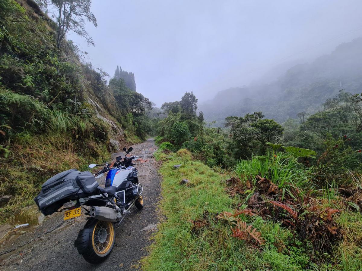  /></a></p><p>Sunt extenuat, ud fleașcă de la ploaie și transpirație deopotrivă, îmi pulsează mușchii picioarelor și antebrațele, îmi bate inima ca unui ogar după o gură de Coca-Cola, iar gândul îmi zboară doar la lipsa de utilitate în alegerea destinației. Ce mi-o fi trebuit? De ce n-am stat eu pe drumul spre Medellin? Să mă duc la un hotel frumos, cu pat mare și așternuturi albe, curate și întinse perfect. Să mănânc ceva bun, să beau o bere la umbră, să mă plimb prin Poblado, cartierul de ”bogați” din oraș? Nu, mie-mi trebuie junglă pentru că am auzit eu că e frumos sus la 3500 de metri pe lângă Manizales.</p><p>Doar că țara asta e atât de tare încât niciun strop de chin nu rămâne fără răsplată. Merg pe drum până sus, până când drumul intră în nori, și ajung în… rai. Un hotel de tip cabană, modernizat, așezat pe coama muntelui. În dreapta, jos, o cascadă care se varsă într-un râu rapid, iar în stânga o mini-pădurice prin care zboară, pe cuvânt de om, zeci de colibri. În spatele hotelului, vizibilă de la drum, o uriașă piscină cu apă termală din care ies aburi. Asta e Columbia, e un exemplu care îmi confirmă regula că într-o perioadă în care Pământul aproape că nu mai are <em>hidden gems</em>, o vizită într-o țară cu o superficial ștampilată reputație rea îți oferă niște surprize plăcute cu care nu prea te mai întâlnești altundeva.</p><p><a href=